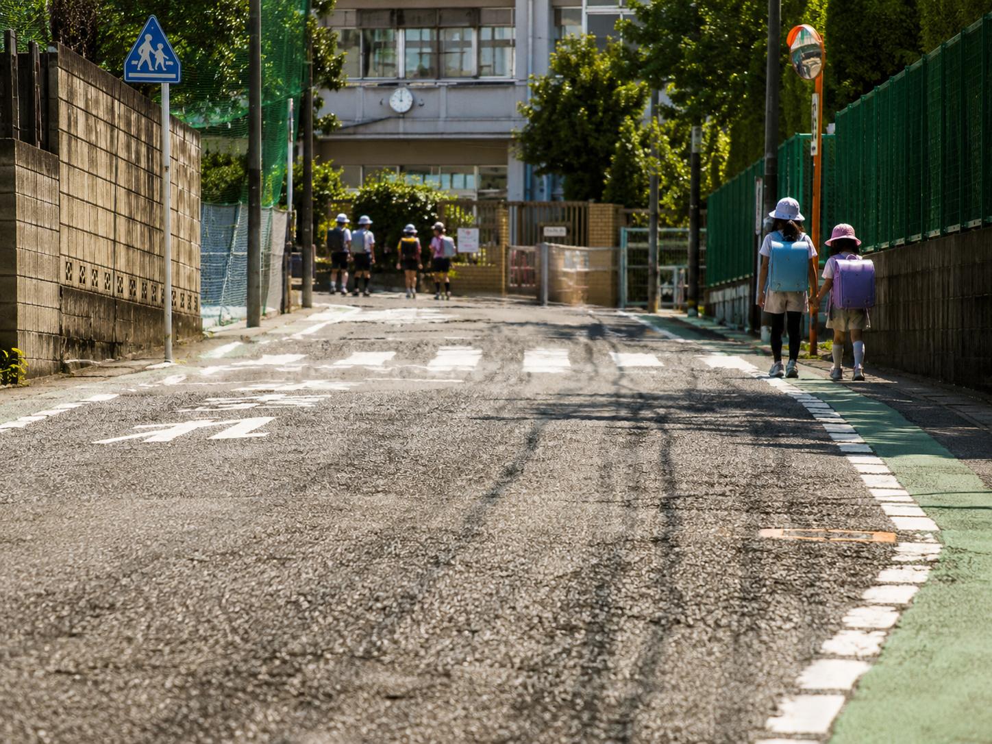 通学路のアスファルトから熱が立ち上がる場面